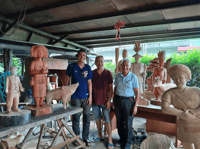 Le père Yves Moal, MEP, et Daniel Maghames entourent Adag dans l'atelier où il fabrique la crèche de Noël.